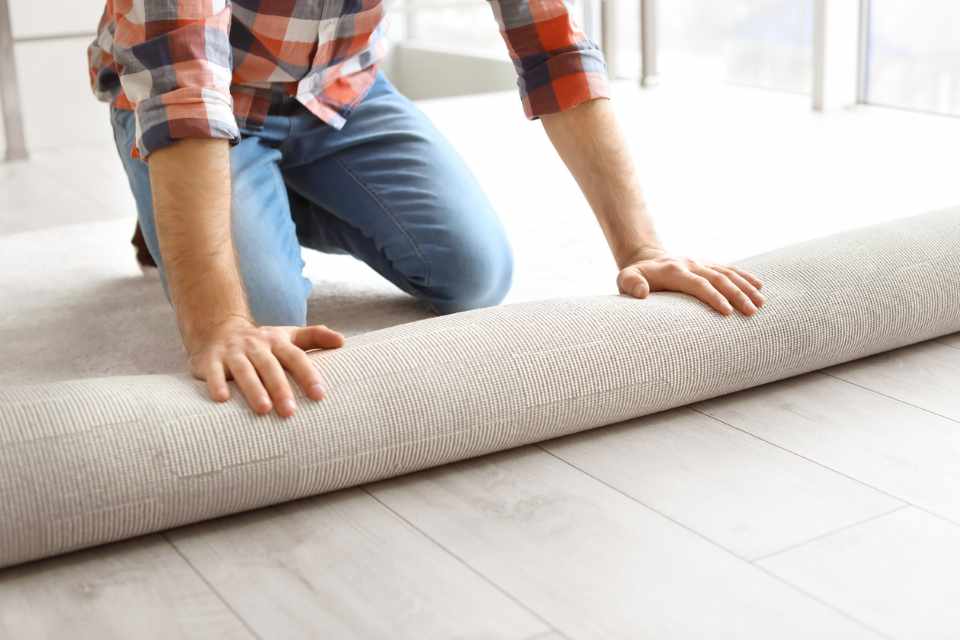 man rolling out carpet in new home